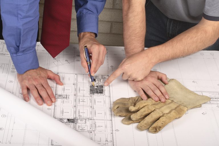 Bauplan: Hände, die auf technische Zeichnungen und Entwürfe zeigen.