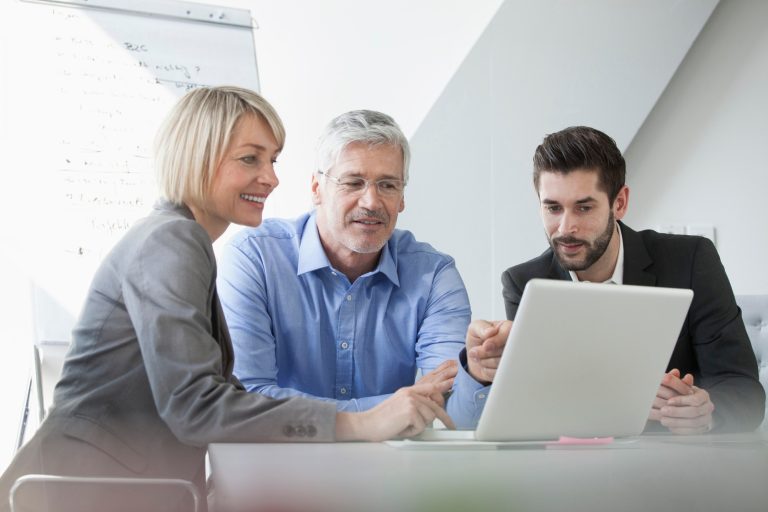 Team-Meeting: Drei Kollegen sitzen zusammen und schauen auf einen Laptop.